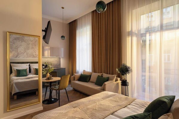 Et hotelværelse med seng, sofa, spisebord og spejl.