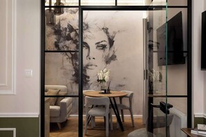 A modern interior with a dining area, a sofa, and a large abstract painting on the wall. - Charm & Chic Suite 26.2 | Main Old Town & Planty (Kraków)