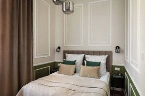 A hotel room with a bed, nightstands, and a wall-mounted lamp. - Charm & Chic Suite 26.2 | Main Old Town & Planty (Kraków)