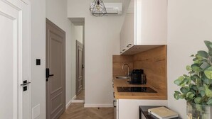 Cocina compacta con encimera de madera, un lavamanos y una lámpara colgante.