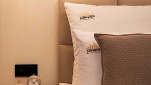 Ein Hotelzimmer mit einem Bett, einem Nachttisch, einer Lampe, einer Uhr und einer Vase.