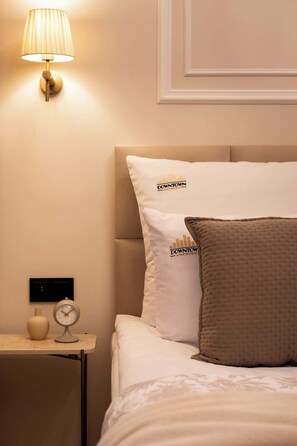 Ein Hotelzimmer mit einem Bett, einem Nachttisch, einer Lampe, einer Uhr und einer Vase.