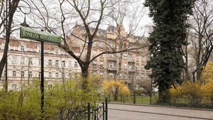 Kadunkyltti, jossa lukee Konrad Swinarski, asfaltoitu kävelyreitti ja klassista arkkitehtuuria edustava rakennus.