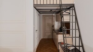 Pieni, käytännöllinen keittiö, jossa on pieni keittotila, metallikaiteella varustetut portaat ja ovi, joka johtaa toiseen huoneeseen.