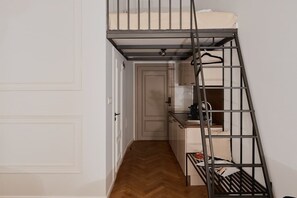 Eine kleine Küche mit Küchenzeile, eine Treppe mit Metallgeländer und eine Tür zu einem anderen Raum.