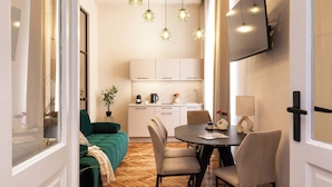Un soggiorno moderno con un divano verde, un tavolo da pranzo con sedie e una cucina sullo sfondo.