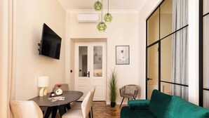 Un soggiorno moderno con zona pranzo, un divano verde e una TV a parete.