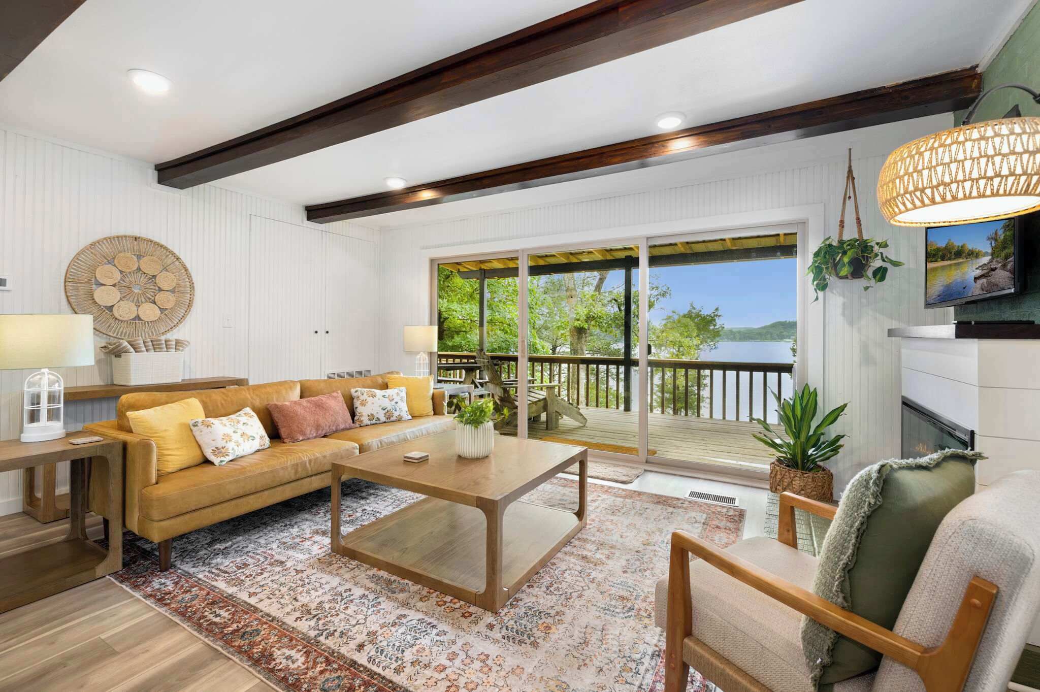 A spacious living room with a large sofa, coffee table, and a view of a lake through the sliding glass doors.