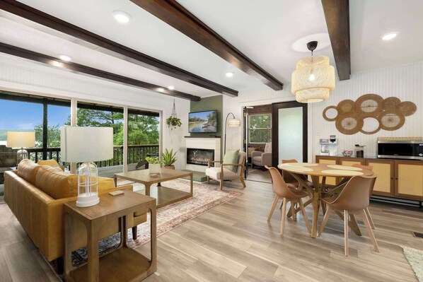 A spacious living area with a fireplace, a dining table, and a kitchen area with a microwave.