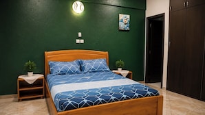 A bedroom with a wooden bed, green walls, a painting, and a wardrobe.