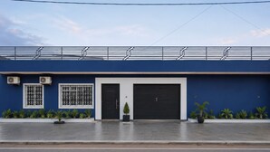 A building with a blue facade, two black doors, and a garage door.
