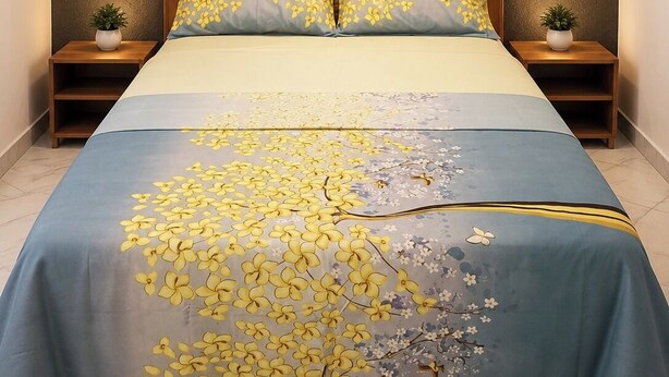 A bed with a floral bedspread, wooden headboard, bedside tables with plants, and a wall-mounted light fixture.