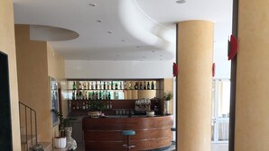 Eine Lobby mit einer gebogenen Rezeption, einem Barbereich mit verschiedenen Flaschen und einem Holzboden.