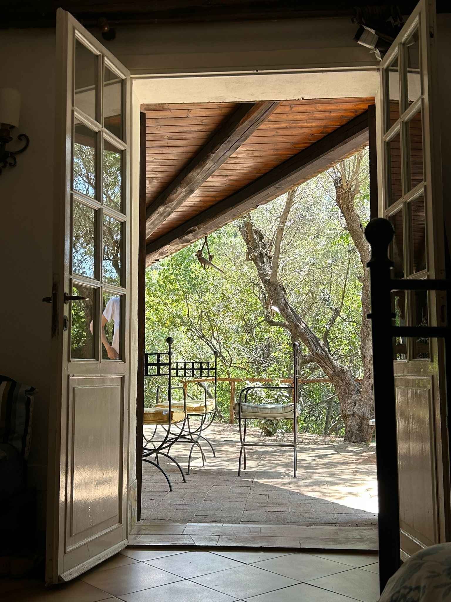 An open doorway leading to an outdoor patio with a wooden ceiling, a table, and chairs.