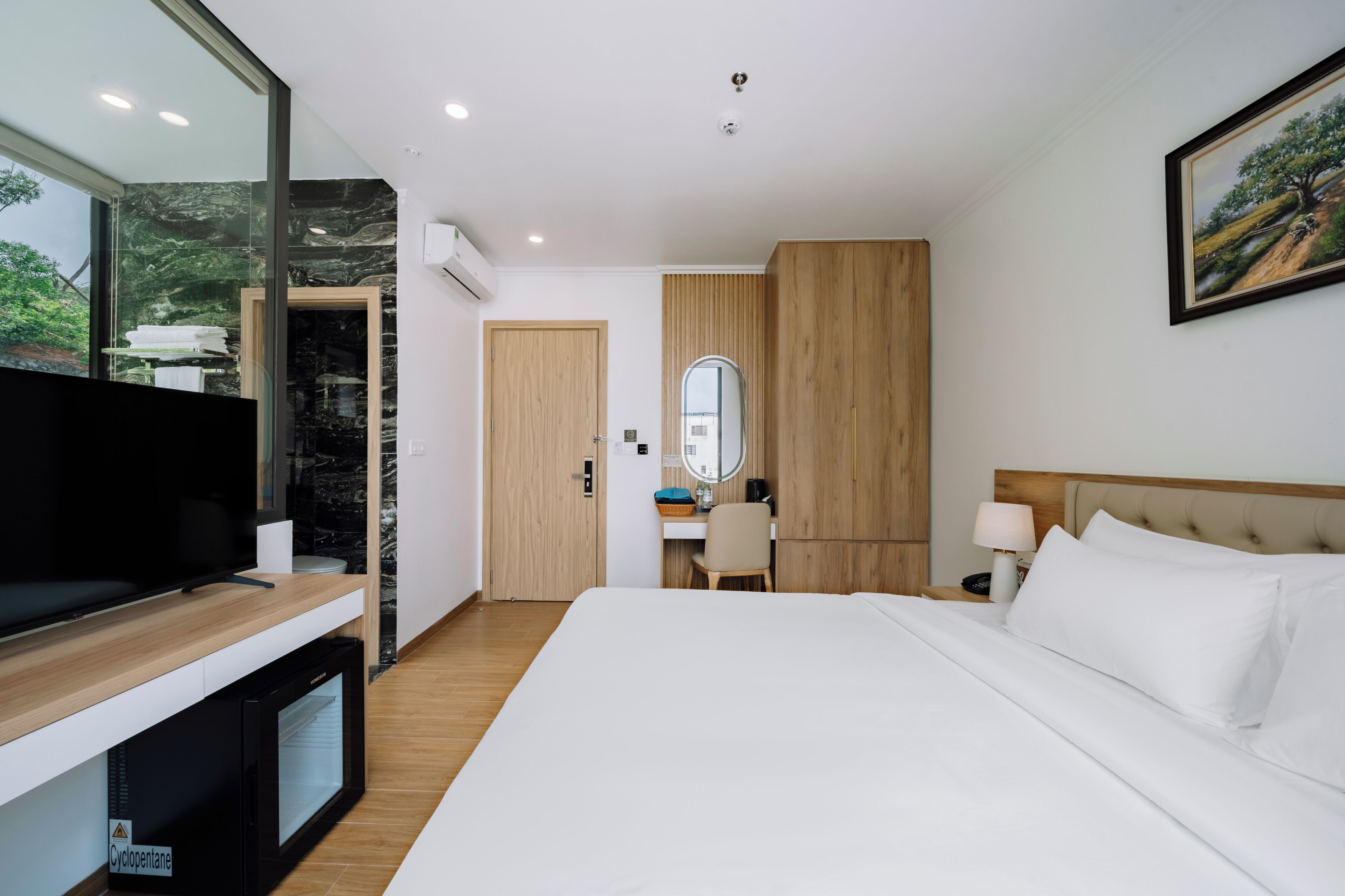 A hotel room with a bed, a desk, a television, and a large mirror.