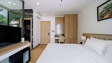 A hotel room with a bed, a desk, a television, and a large mirror.