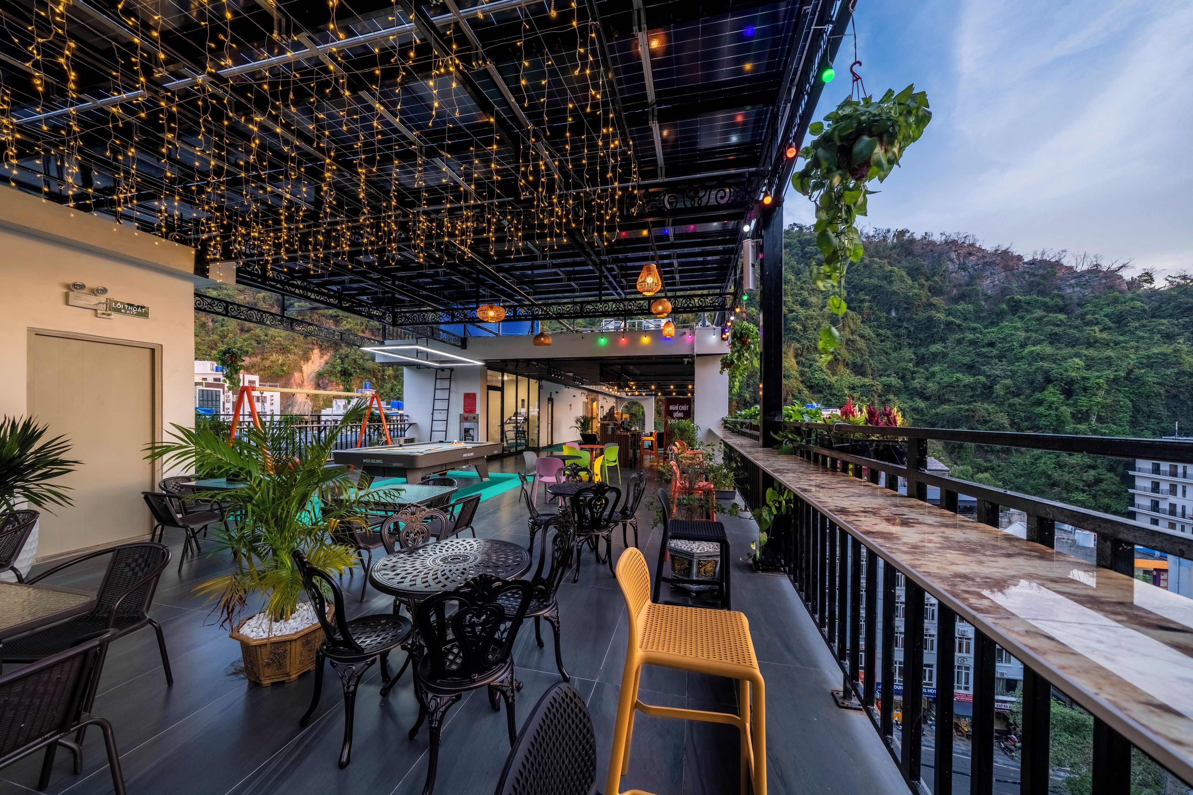 An outdoor seating area with tables and chairs, a pool table, and string lights.