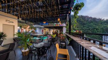 An outdoor seating area with tables and chairs, a pool table, and string lights.
