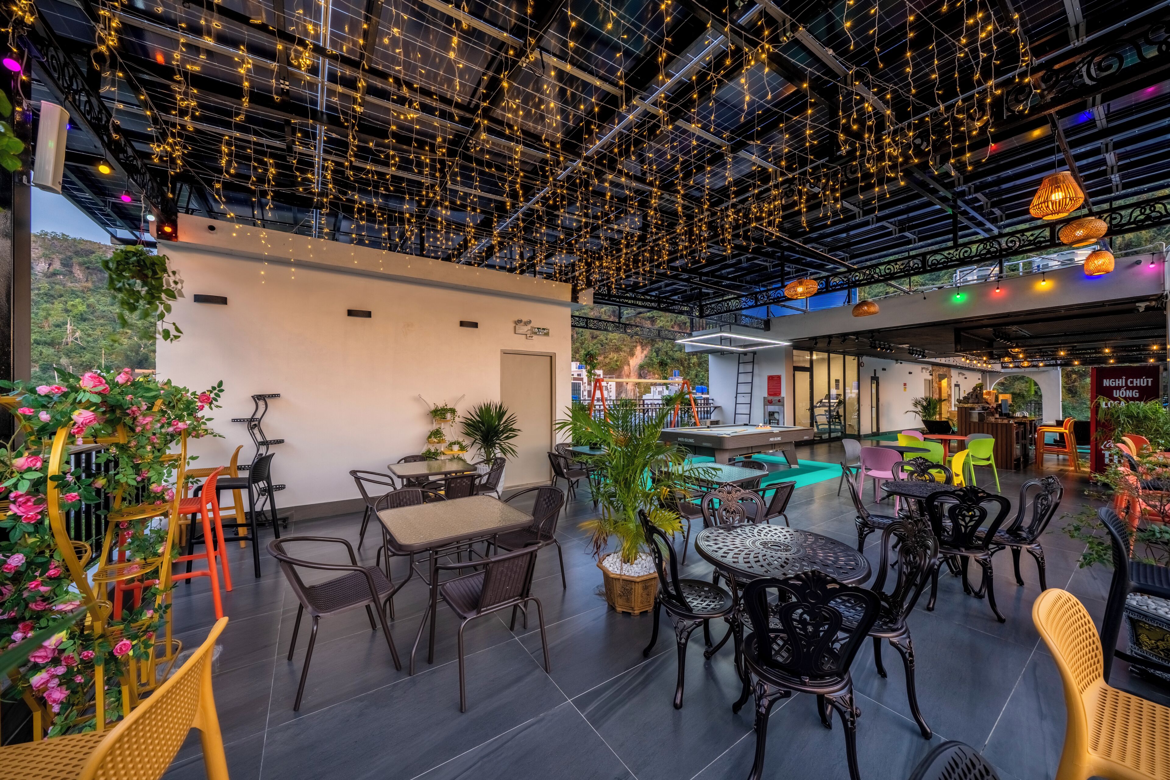 Un café intérieur avec des tables et des chaises, un billard et des plantes décoratives.
