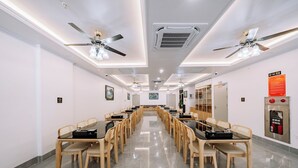 A conference room with long tables, chairs, ceiling fans, and a fire extinguisher. - Catba Vista Hotel (Hai Phong)