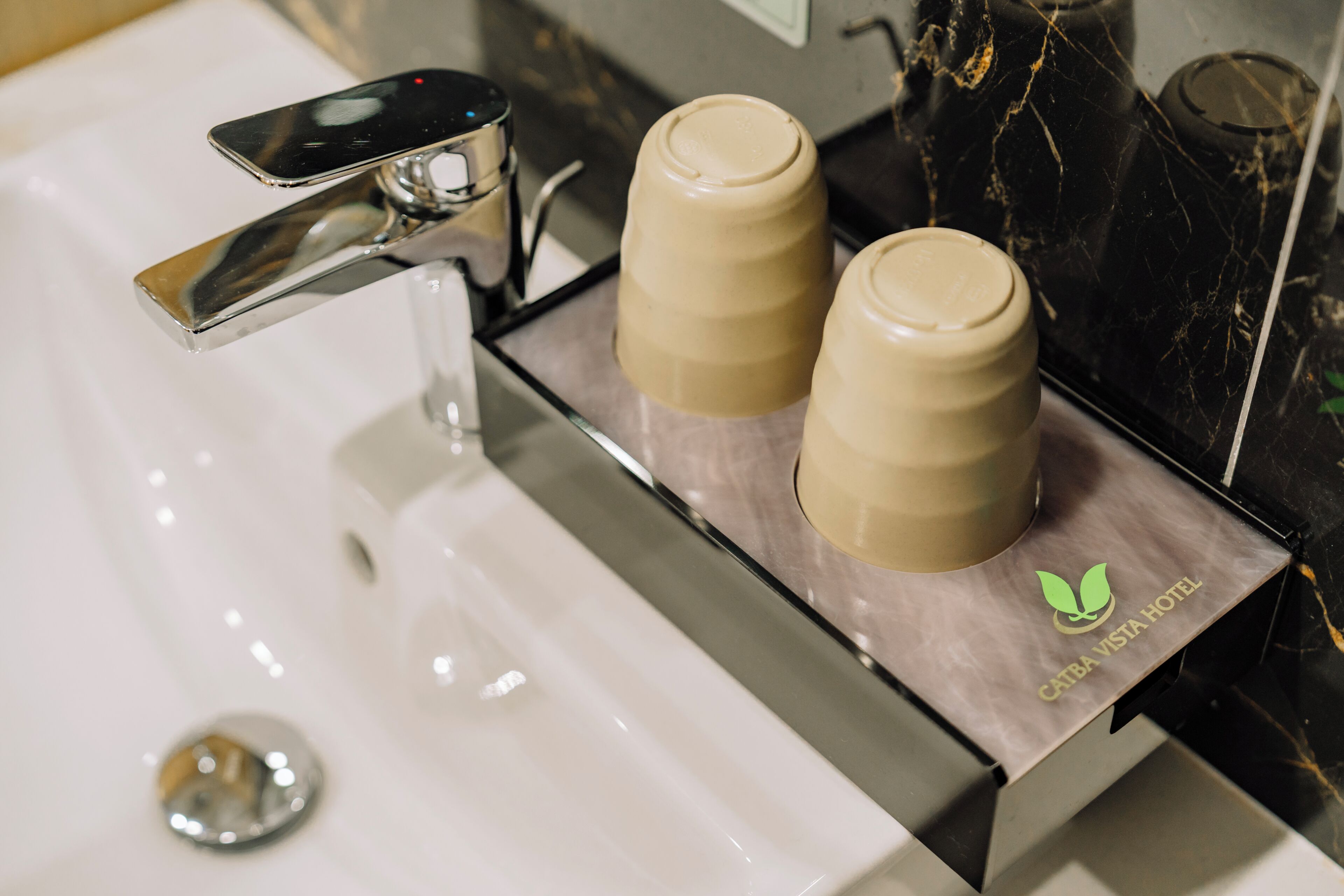 A bathroom sink with a modern faucet and two beige bottles on a marble countertop.