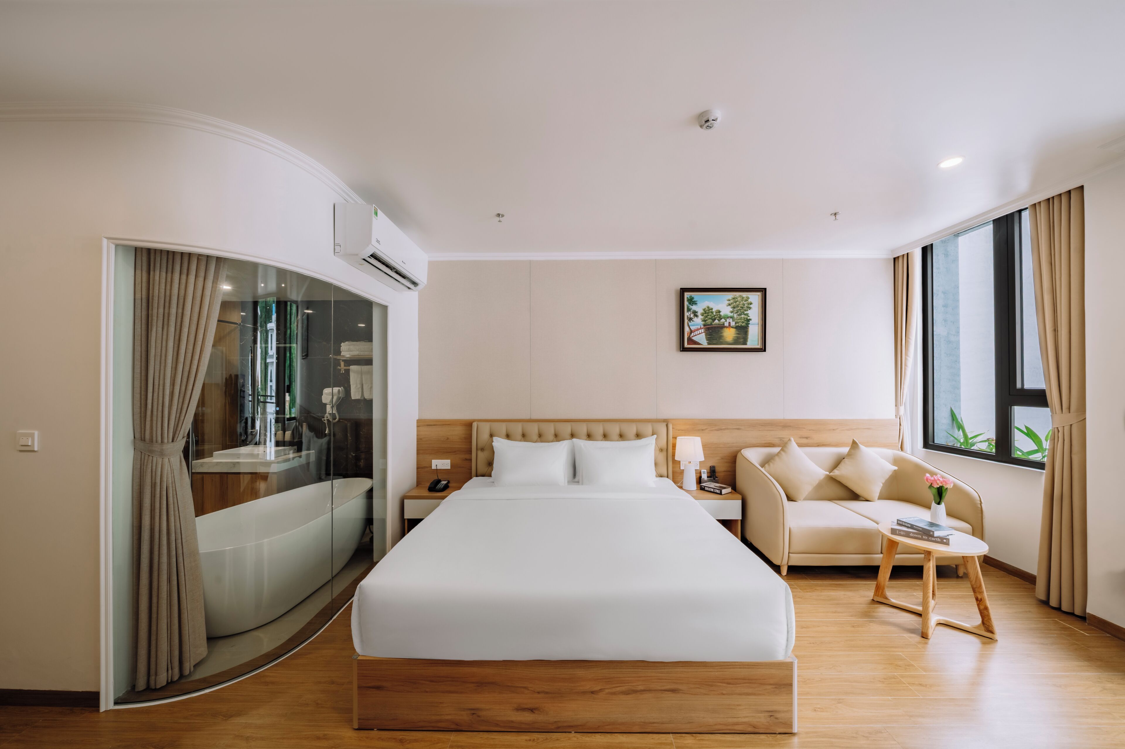 Habitación de hotel con una cama grande, un sofá, una mesita y una ventana con cortinas.