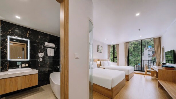 A hotel room with a bathroom, two beds, a desk, and a balcony with a view. - Catba Vista Hotel (Hai Phong)