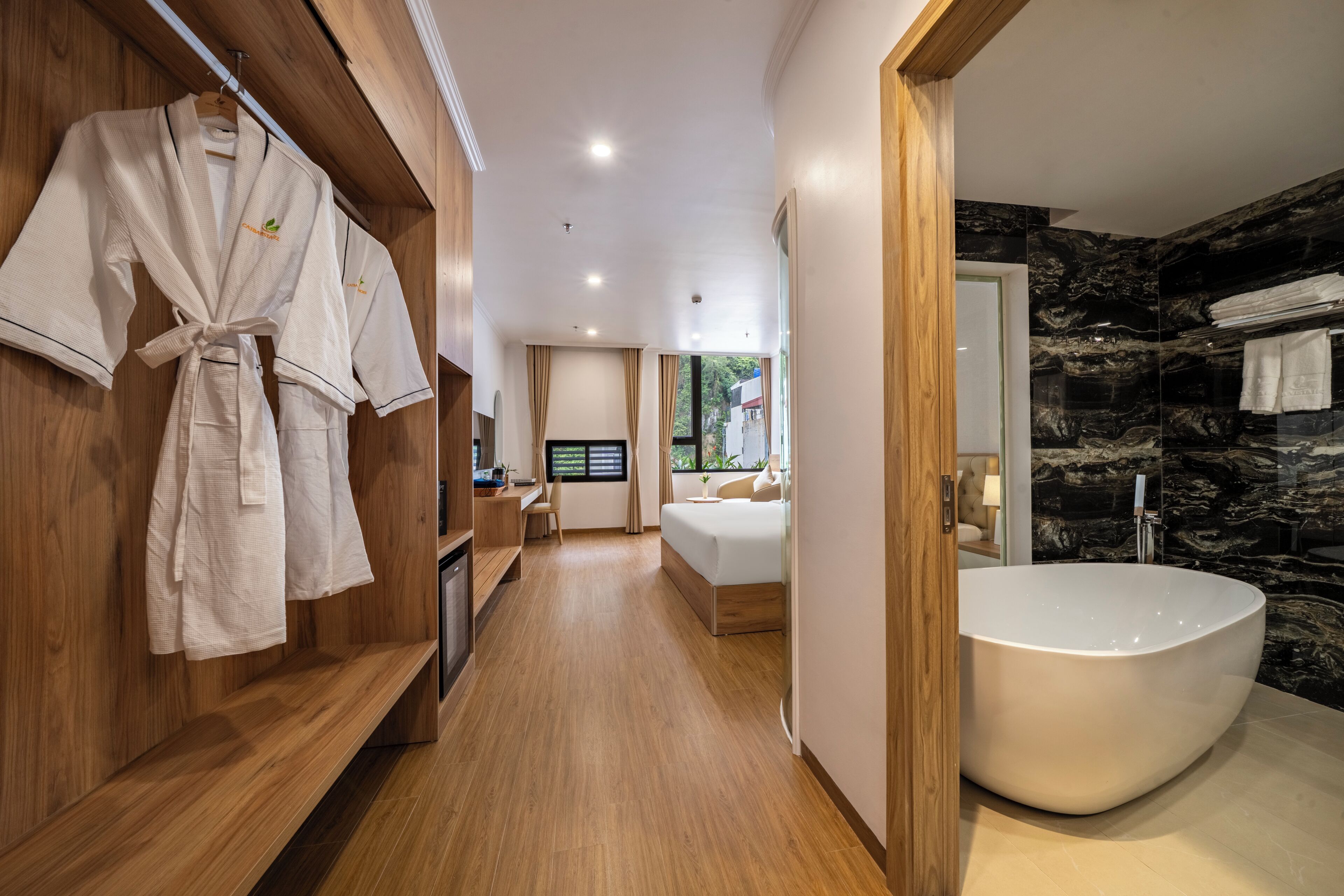A modern bathroom with a large bathtub, wooden flooring, and a robe rack.