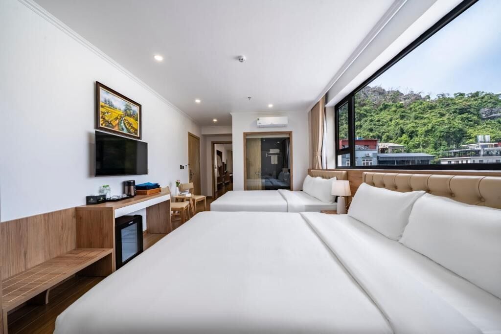Une chambre d’hôtel avec deux lits, une télévision, un bureau et une fenêtre donnant sur un paysage urbain.