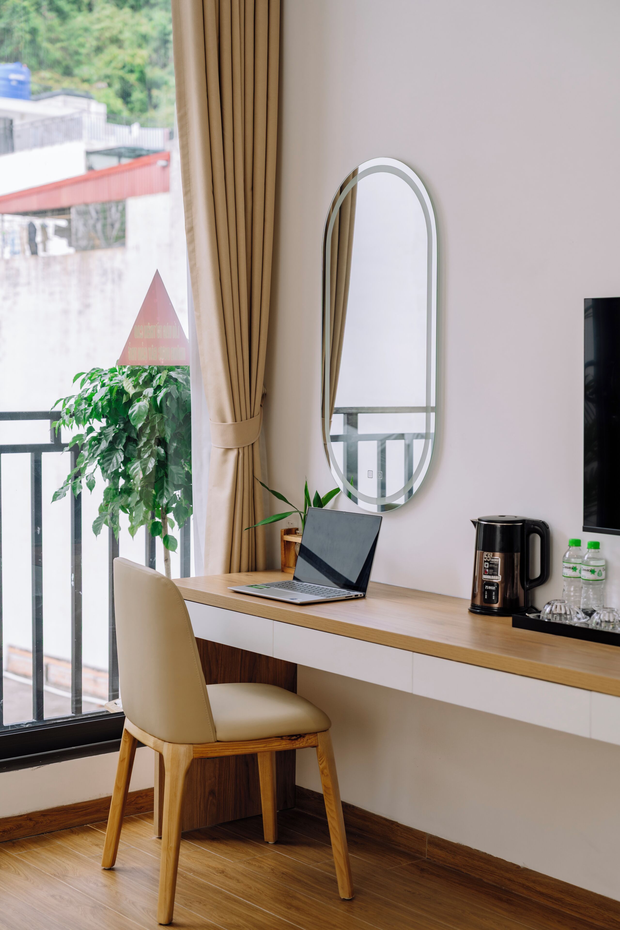 A room with a desk, a chair, a laptop, a coffee maker, and a potted plant.