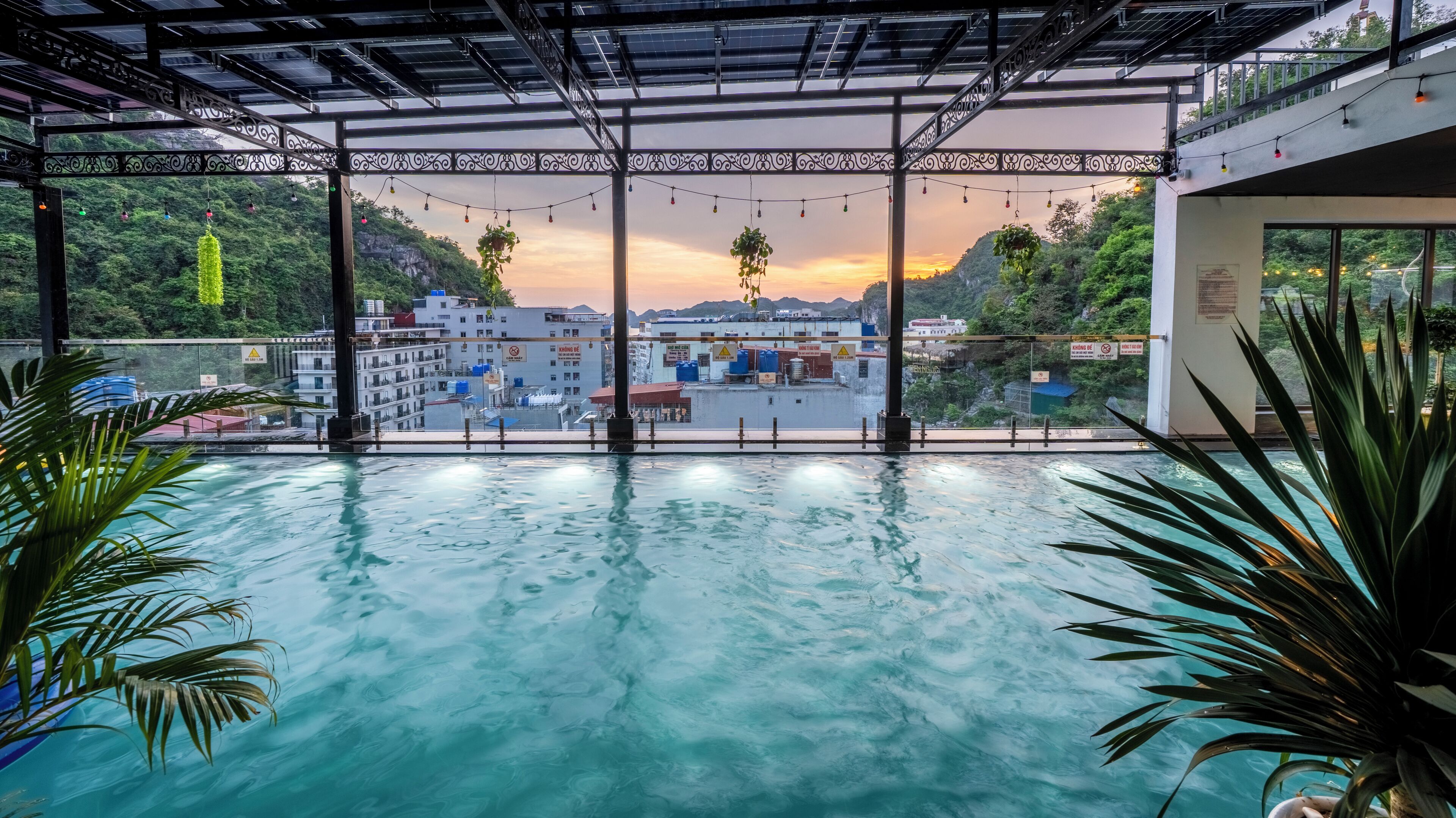 An indoor swimming pool with a view of buildings and a sunset.