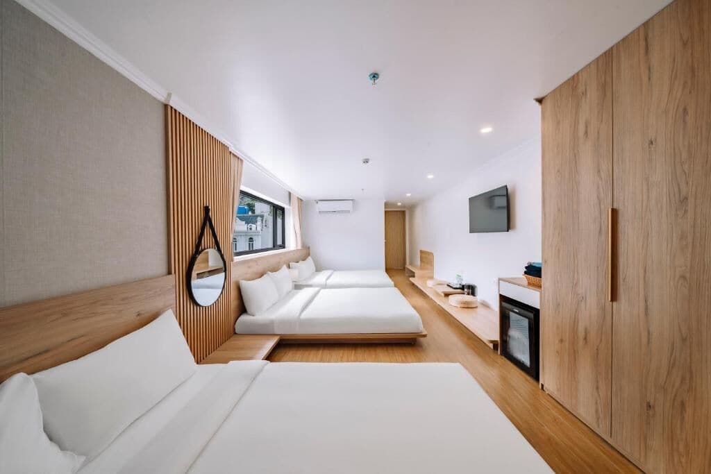 A modern hotel room with a large bed, a bedside table, a mirror, and a TV mounted on the wall.