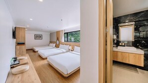 A hotel room with two beds, a wooden bedside table, a small seating area, a large window, and a bathroom with a black marble countertop. - Catba Vista Hotel (Hai Phong)