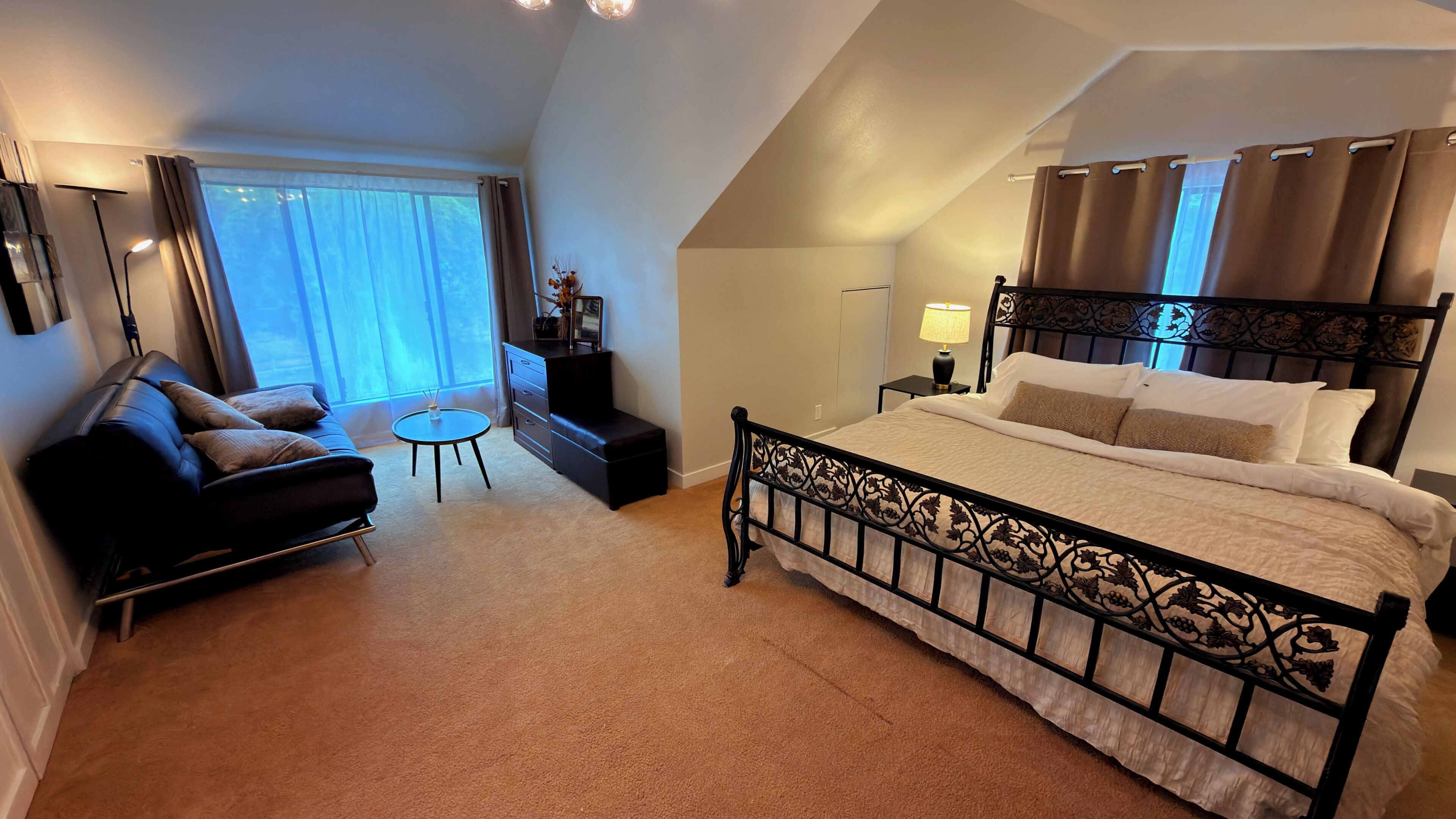 Een slaapkamer met een bed, een bank, een bijzettafeltje en een nachtkastje.