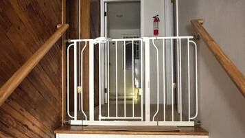 A wooden staircase with a white railing and a fire extinguisher mounted on the wall.