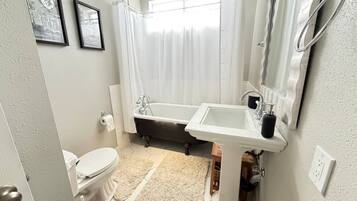 A bathroom with a bathtub, toilet, sink, and a shower curtain.
