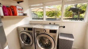 A laundry area with two front-loading washing machines, a drying rack, and a trash bin. - Mountain Cabin With Hot Tub & Fire Pit, Wallace Falls & Stevens Pass (Gold Bar)