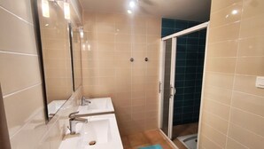 Ein Badezimmer mit zwei Waschbecken, einem Spiegel und einer Duschkabine.