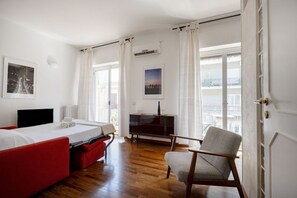 Una camera da letto con un letto, un divano rosso, una TV e una sedia.