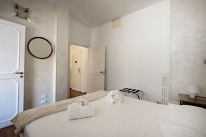 Ein Hotelzimmer mit Bett, Handtuchhalter, Heizkörper und einer Tür zu einem anderen Raum.