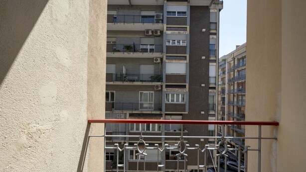 Ein mehrgeschossiges Wohngebäude mit Balkonen, Klimaanlagen und Blick auf die Straße.