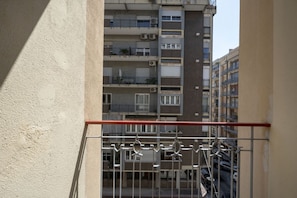 Ein mehrgeschossiges Wohngebäude mit Balkonen, Klimaanlagen und Blick auf die Straße.