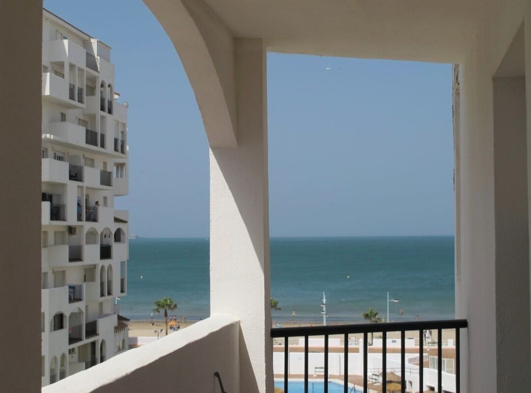 Un balcon donnant sur la mer et un immeuble doté de nombreux balcons.