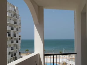A balcony with a view of the sea and a building with multiple balconies.