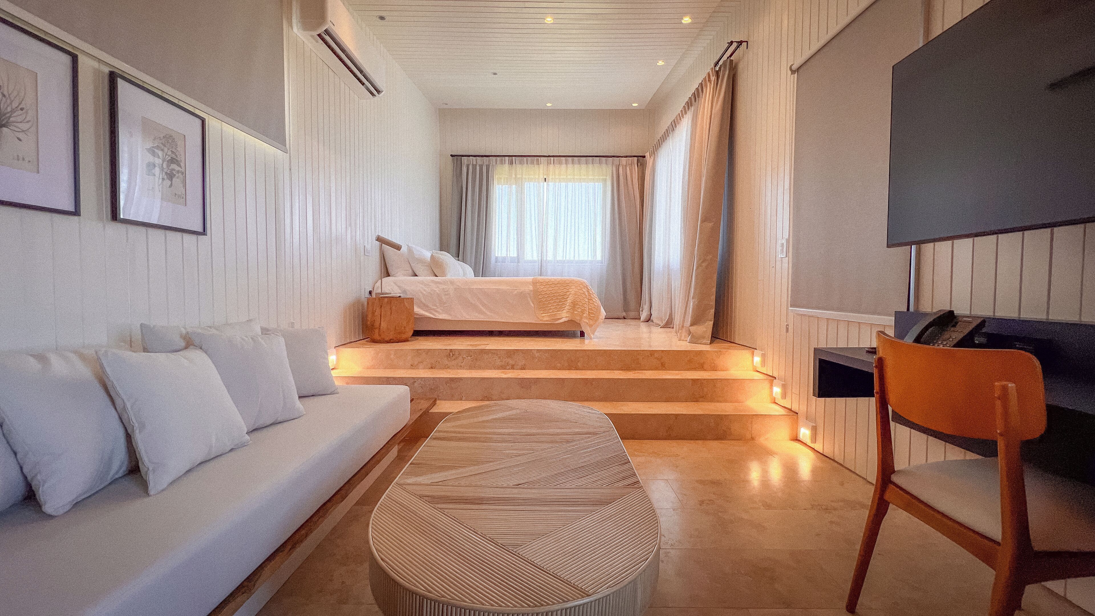 Un dormitorio moderno con cama, sofá, sillón y televisión.