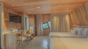 A hotel room with a wooden ceiling, a desk with chairs, a bed, and a television mounted on the wall. - Locus Solus Hotel Singular (Mar del Plata)