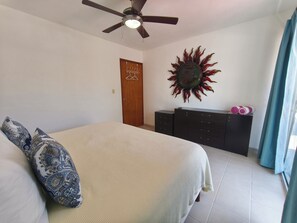 A bedroom with a bed, a ceiling fan, a wardrobe, and a decorative wall piece. - Azul Mar Apartment 2 (Puerto Morelos)