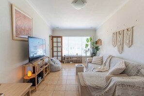 A living room with a television, bean bag, sofa, and macrame wall decor. - Cosy & Central Apartment: Fast Wifi, Walk to beach (Scarborough)