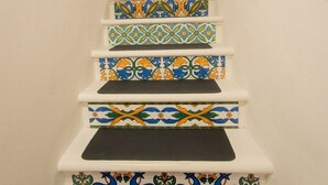 Eine Treppe mit farbenfrohen, gemusterten Stufen, die zu einer Tür führt.