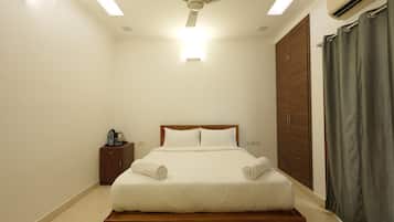 A bedroom with a bed, a nightstand, a wardrobe, a ceiling fan, and an air conditioning unit.